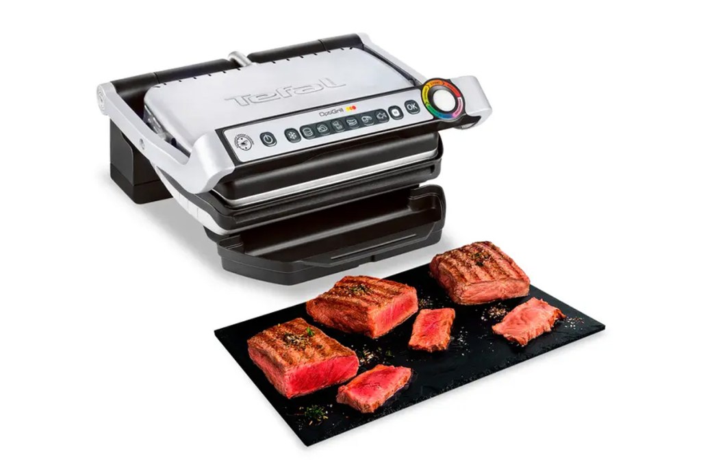 Der Optigrill GC705D von Tefal auf weißem Hintergrund. Davor Steaks mit unterschiedlichem Gar-Grad auf einem Teller.