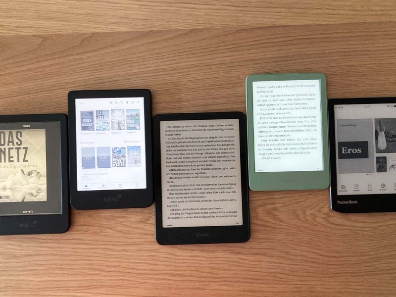 5 eBook-Reader auf einer Holzplatte liegend