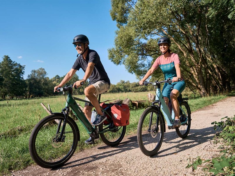 Zwei Menschen fahren mit einem E-Bike durch die Natur