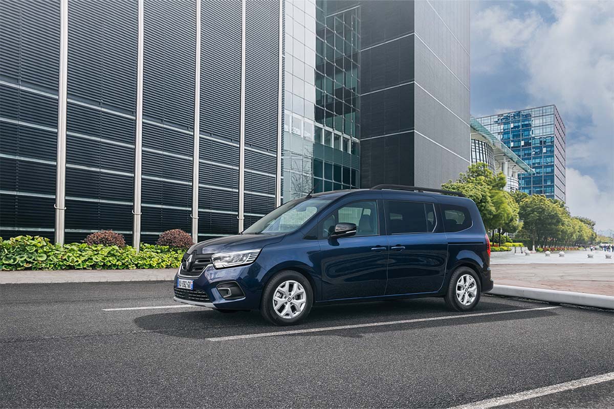 Renault Grand Kangoo E-Tech Electric auf einer Straße, im Hintergrund Bürogebäude