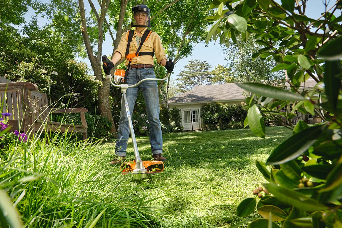 Ein Mann benutzt im Garten eine Akku-Sense