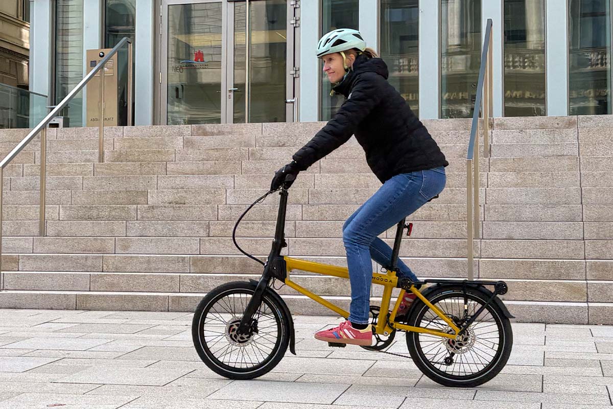 Frau fährt auf einem gelben Falt-E-bike über einen Platz