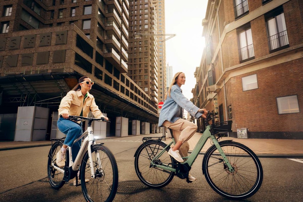 zwei Frauen fahren mit einem E-Bike durch die Stadt
