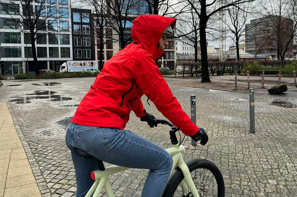 Frau mit Regenjacke auf E-Bike auf Marktplatz.