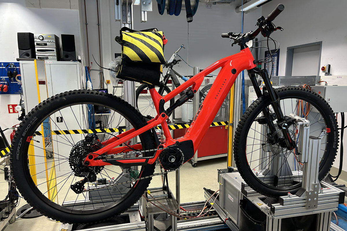 Rotes E-Bike steht im Profil auf einem Teststand im Labor von Qima/IMTEST.