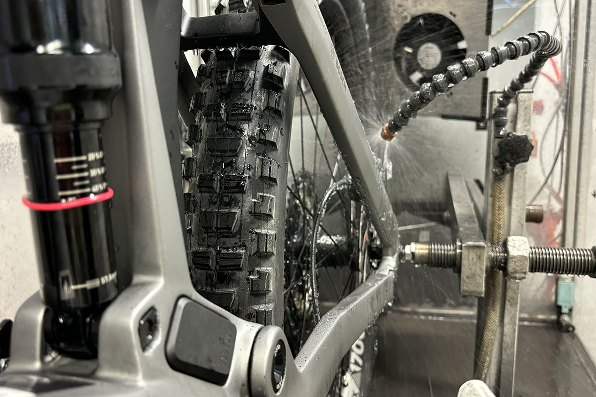 Detailaufnahme von einem Hinterrad eines E-Bikes das in einem Bremsenteststand begfestigt ist. Für die Prüfung der Scheibenbremsen im feuchten Zusatnd wird Wasser auf die Scheibenbremsen gesprüht.