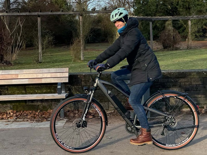 Frau fährt mit einem E-Bike durch einen Park