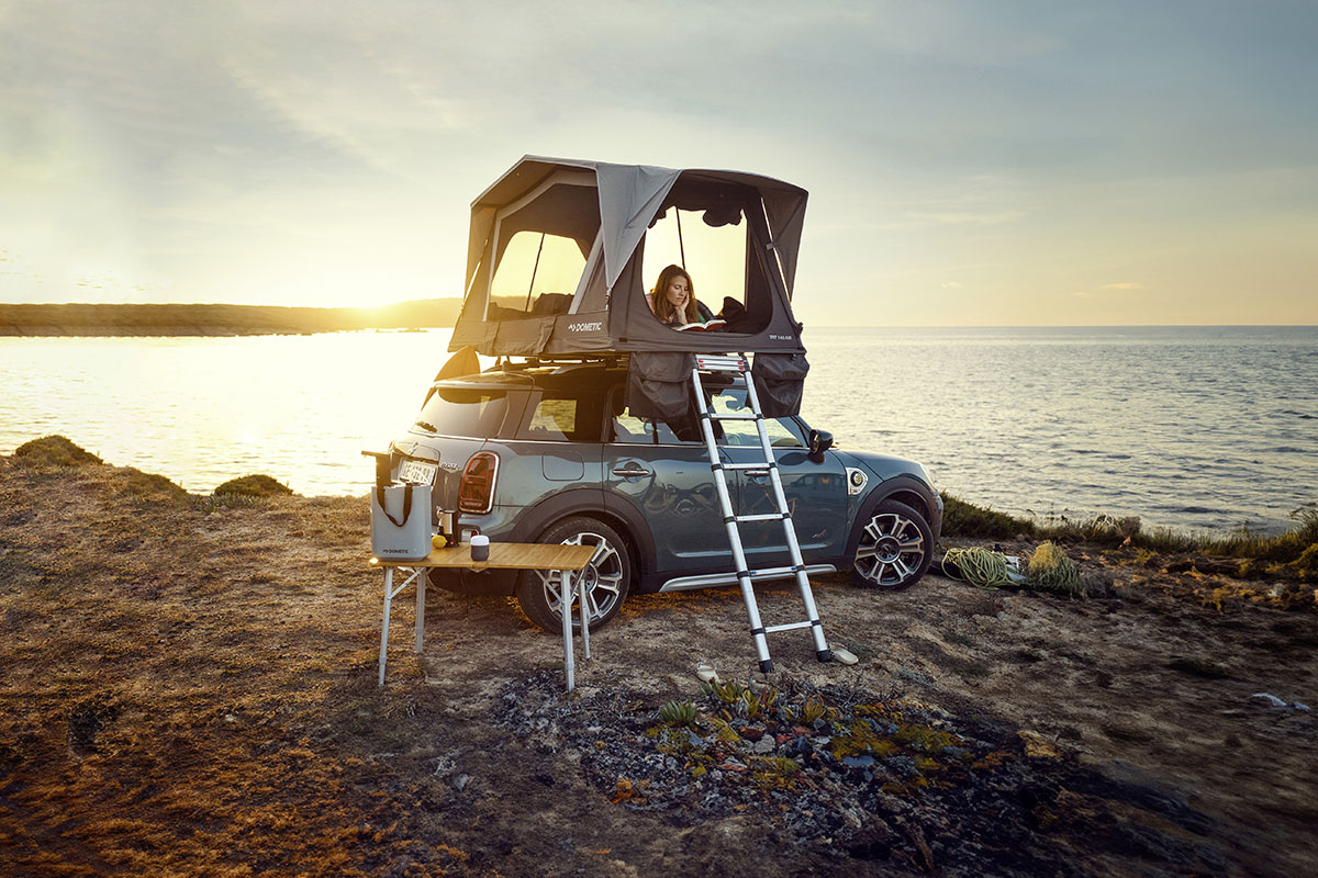 Dachzelt von Dometic auf einem Mini Cooper montiert, der auf einer Steilüste über dem Meer stehtr.