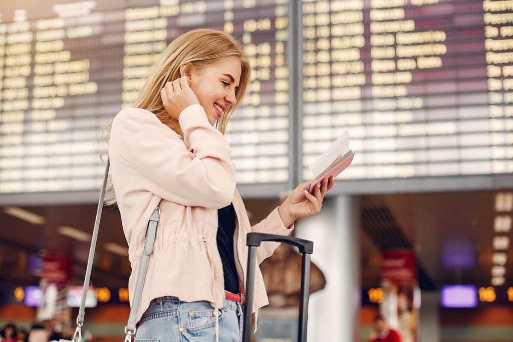 Eine blonde Frau steht am Flughafen.