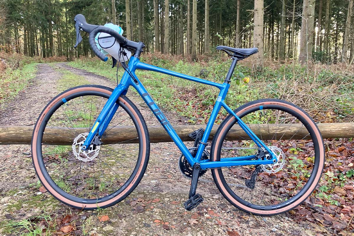 blaues E-Bike lehnt vor einer Baumschranke, Wald im Hintergrund