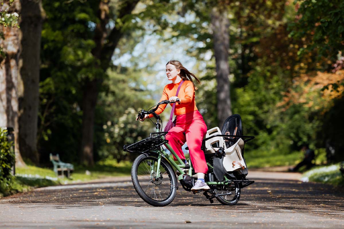 Frau fährt mit einem kompakten Cargo-LE-Bike durch einen Park