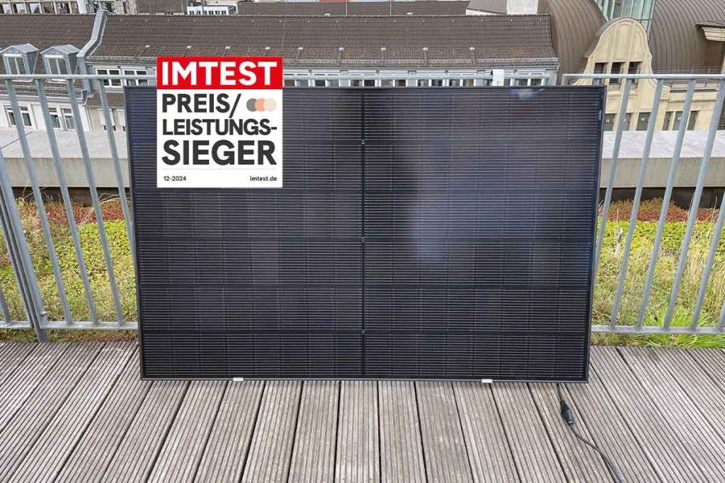 Das Testmodell von kleines Kraftwerk auf einer Dachterrasse an einem Geländer. Davor eingefügt das IMTEST-Preis-Leistungssieger-Siegel 12-2024.