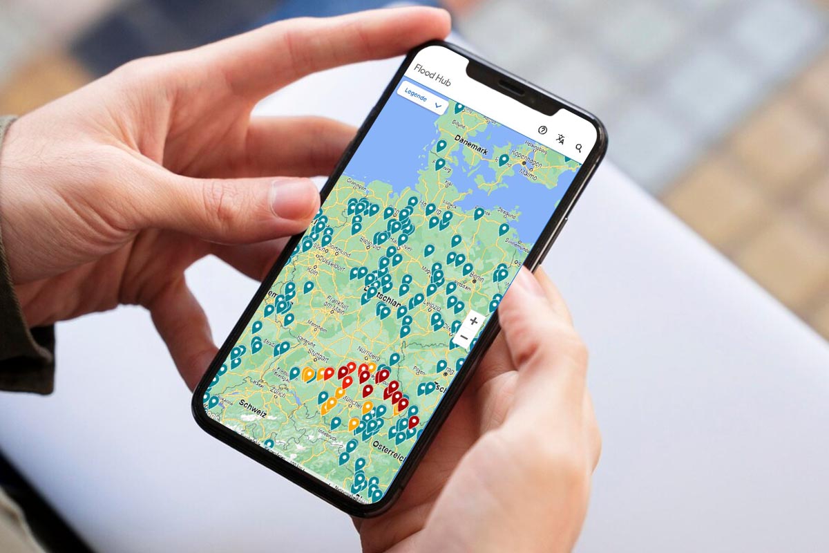 In der Hand gehaltenes Smartphone mit geöffneter "Flood Hub" Website.