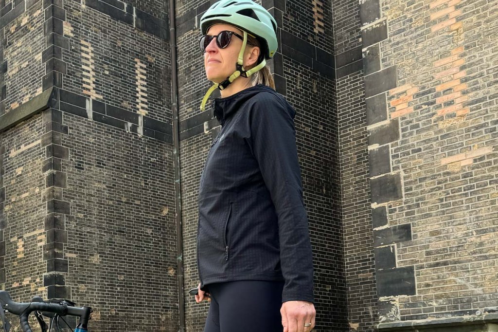 Frau steht neben ihrem Fahrrad, sie trägt eine schwarze Fleecejacke