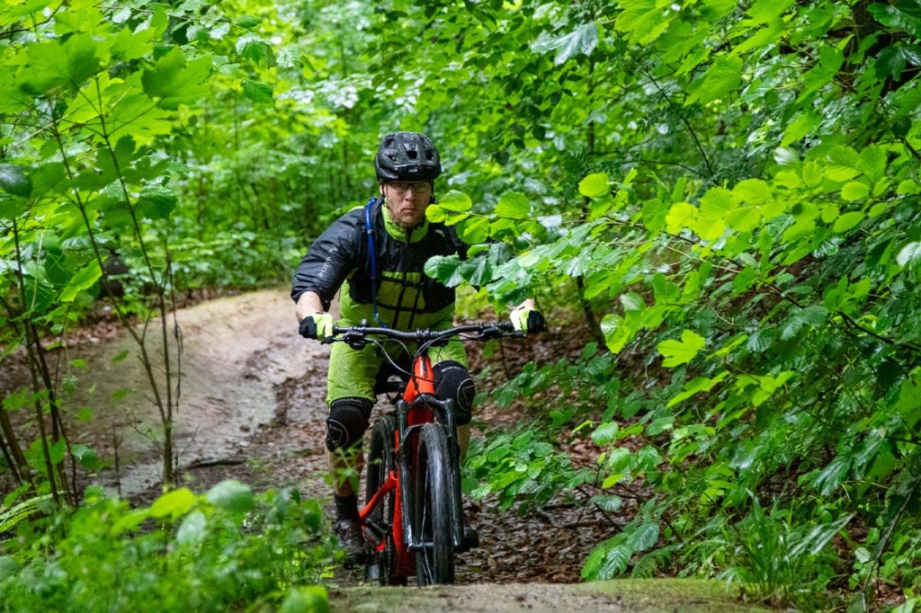 Person fährt mit einem Mountainbike durch den Wald, kommt auf die Kamera zu