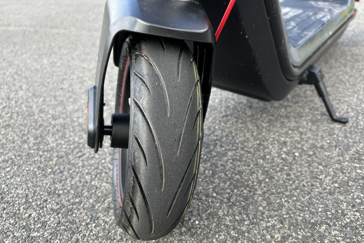 Detailaufnahme eine E-Scooter Reifens (Vorderrad), der auf einer Straße steht.