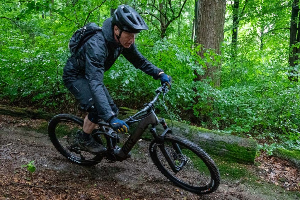 Mann fährt mit einem Mountainbike einen steilen Trail im Wald