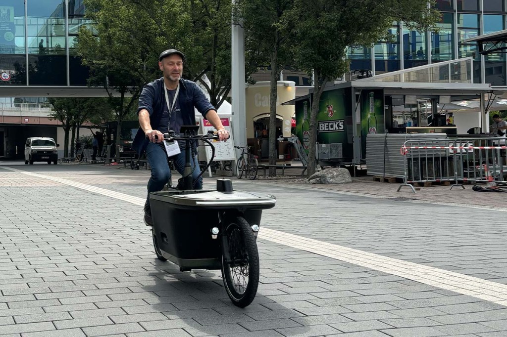 Mann fährt mit einem Cargo-E-Bike über einen Platz