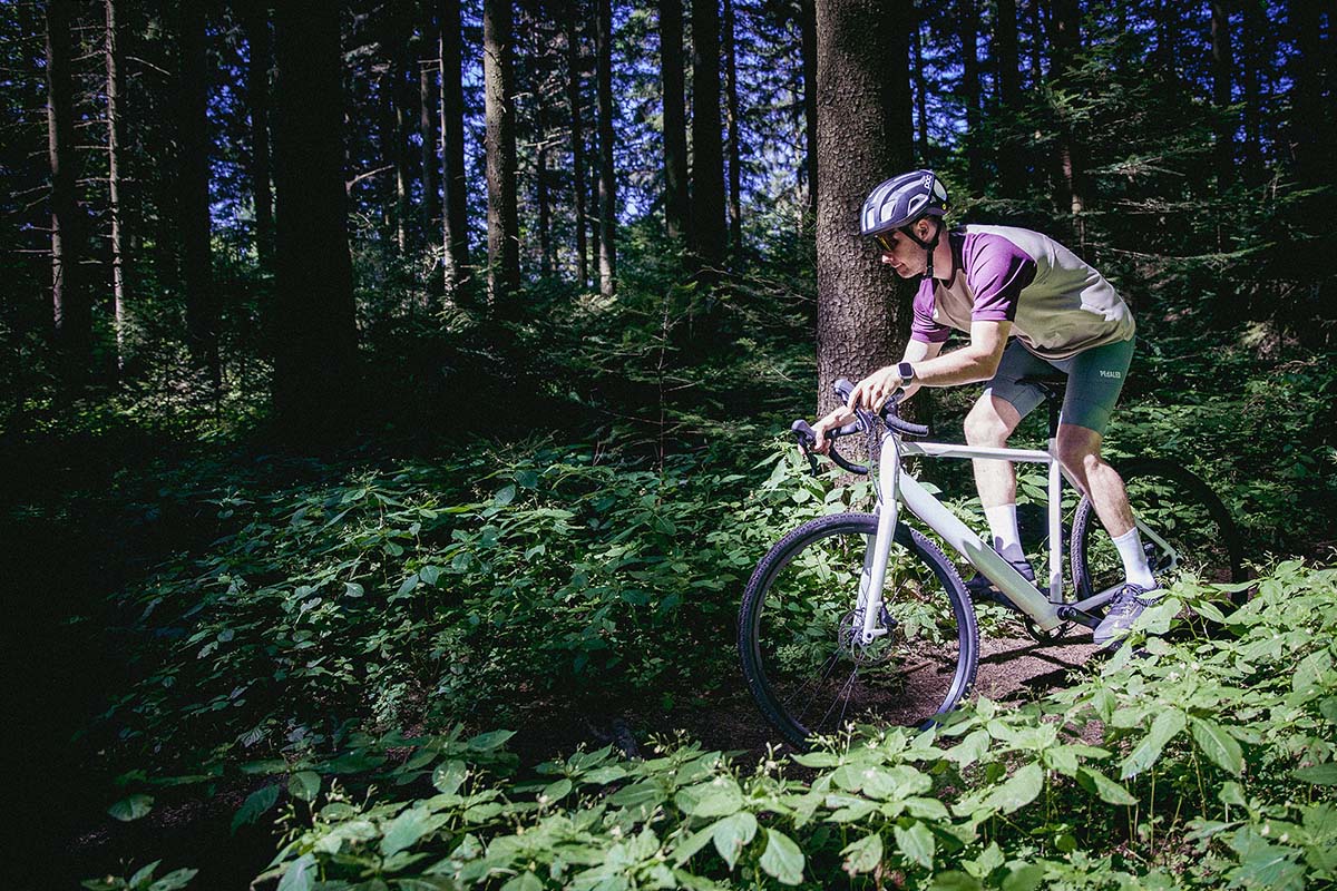 Person mit einem Gravel-E-Bike, die durch den Wald fährt