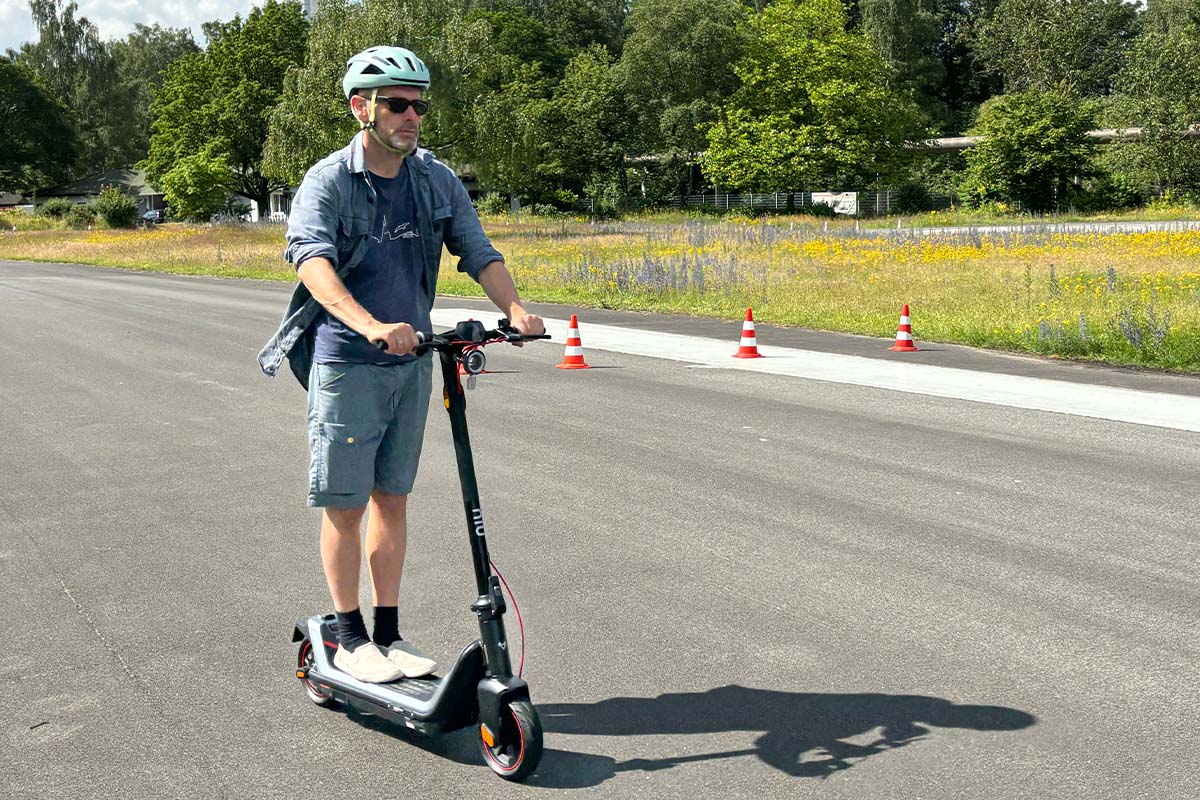 Mann fährt mit einem E-Scooter über eine Straße