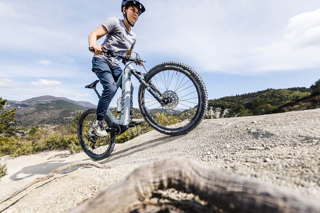 Frau fährt mit einem E-Mountainbike über eine hügelige SChotterpiste