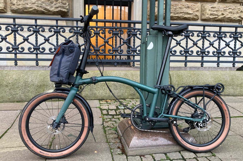 grünes Falt-E-bike vor einem Lampenmast lehnend