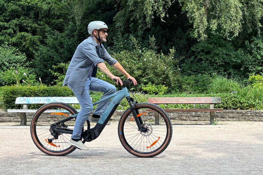 Mann fährt mit einem E-Mountainbike durch einen Park