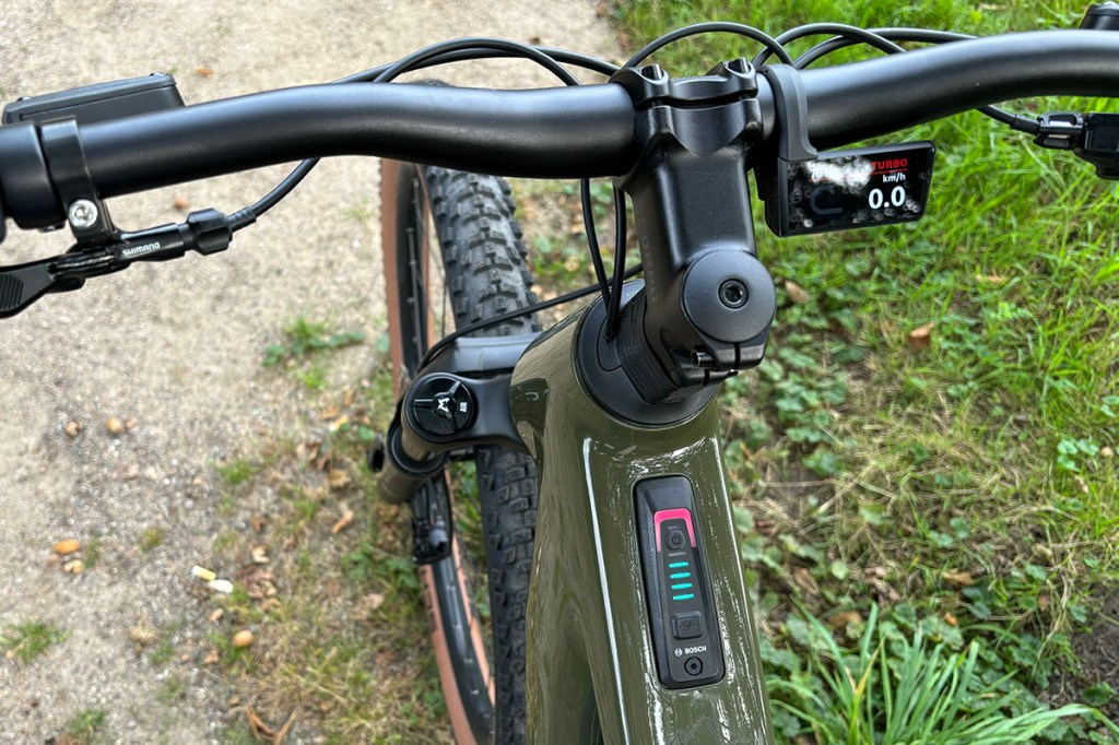 Detailansicht eine E-Bike-Lenkers mit kleinem Fahrdisplay, das rechts von der Lenkerstange angebracht ist.