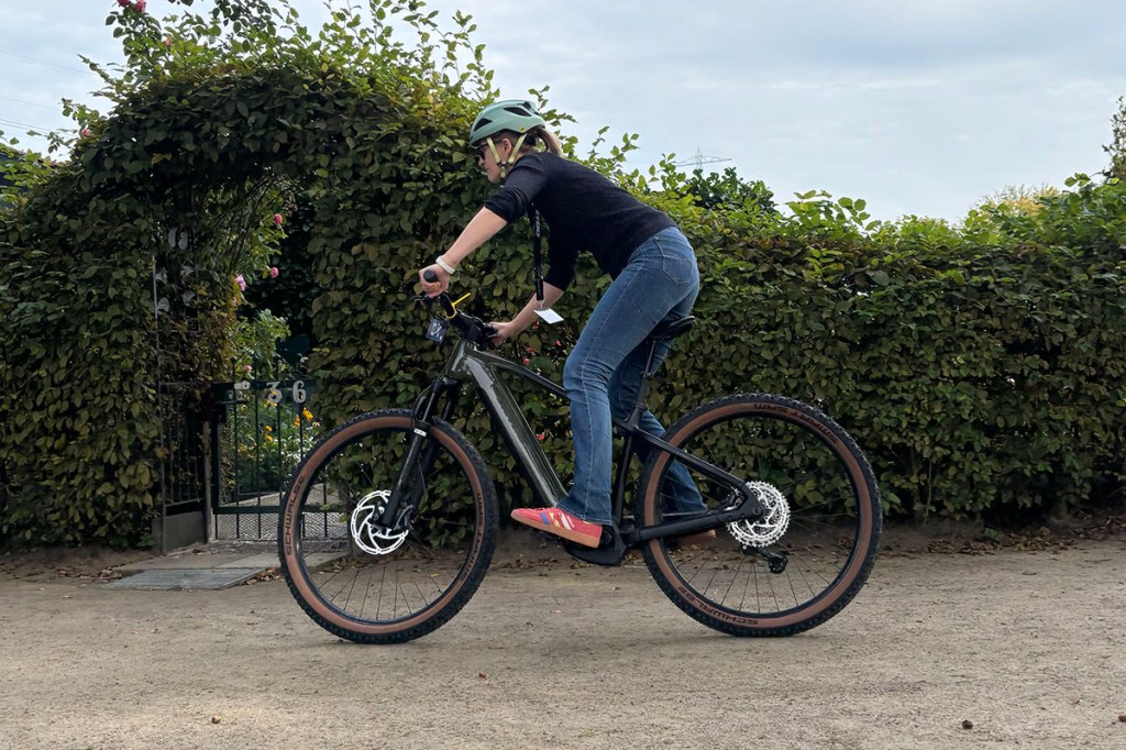 Frau fährt schwungvoll mit E-Mountainbike um eine Kurve.