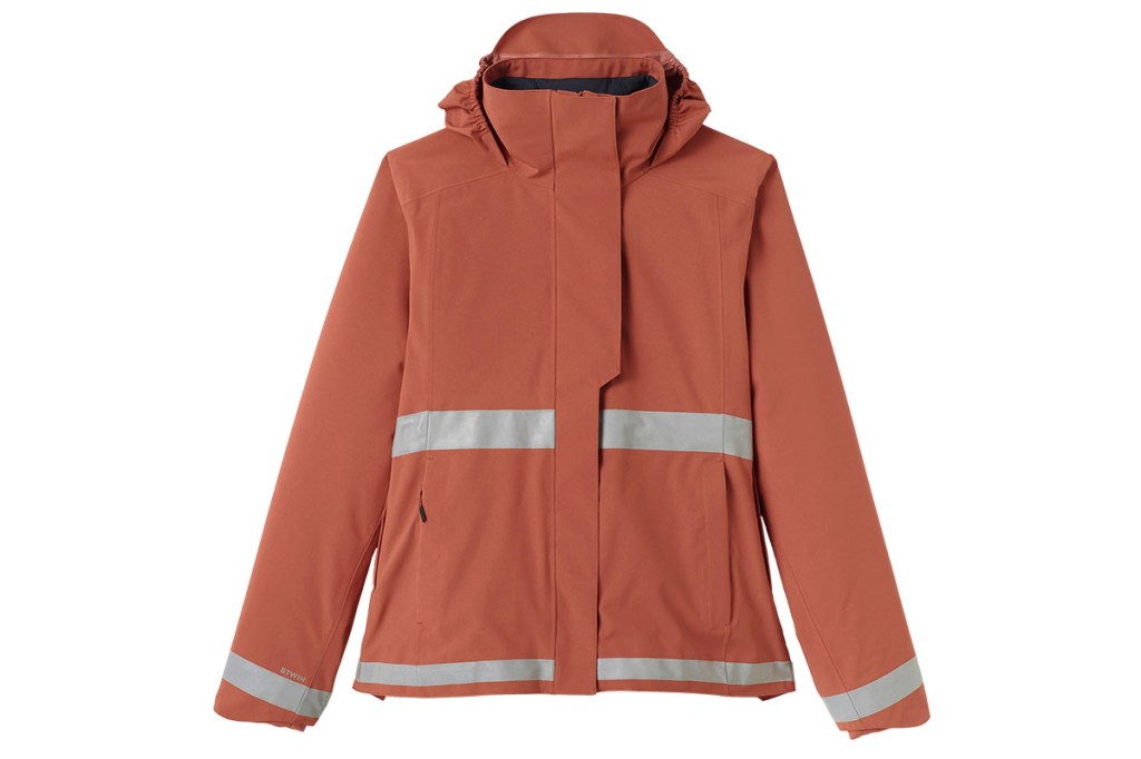 Orange Regenjacke mit Reflektorstreifen um den Bauchbereich von Decathlon liegt ausgebreitet vor weißem Hintergrund.