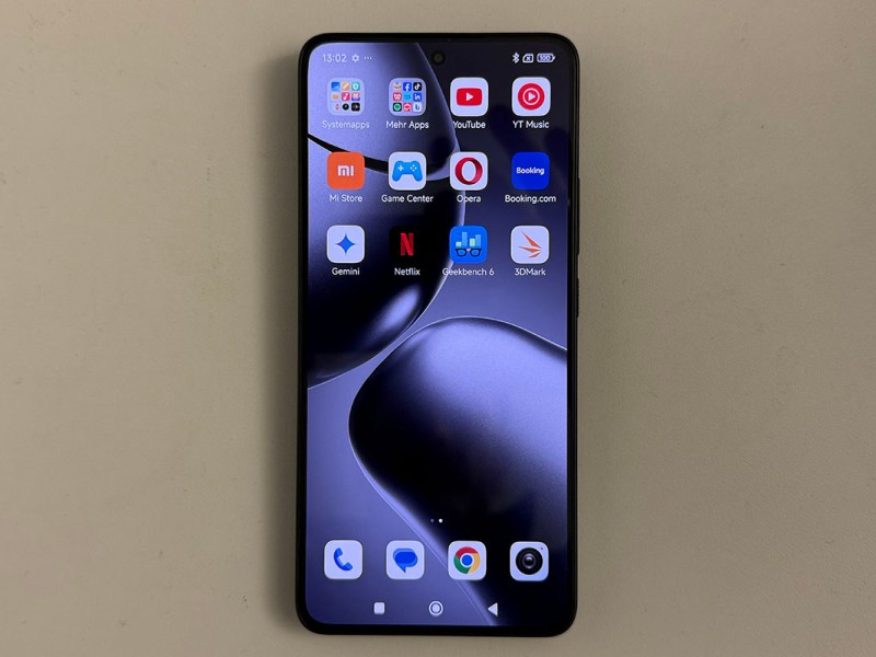 Smartphone Xiaomo 14T in frontaler Ansicht mit eingeschaltetem Display, das unterschiedliche App-Symbole anzeigt. Das Gerät liegt auf einer weißen Tischplatte.