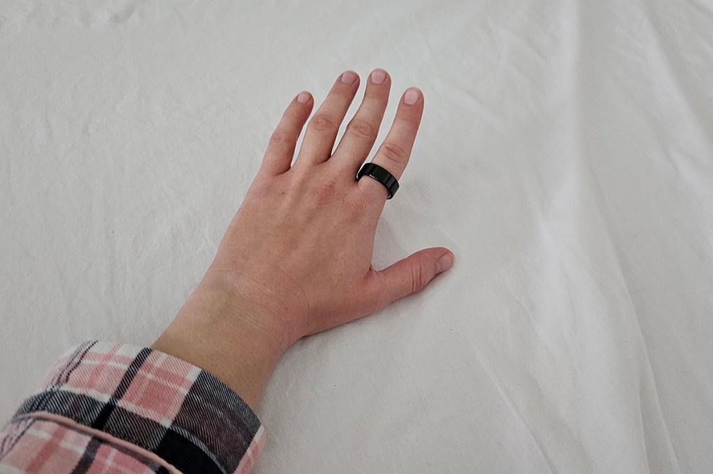 Oura Ring 4 an einer Hand in einem Bett