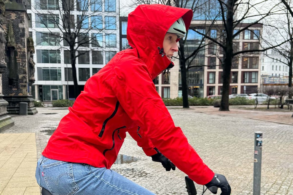 detailaufnahme, Frau auf einem FAhrrad, trägt eine rote Regenjacke