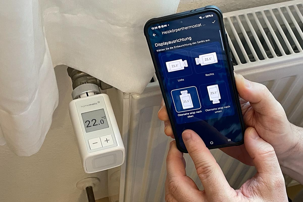 Das Heizkörperthermostat Flex von Homematic IP mit der dazugehörigen App auf dem Smartphone.