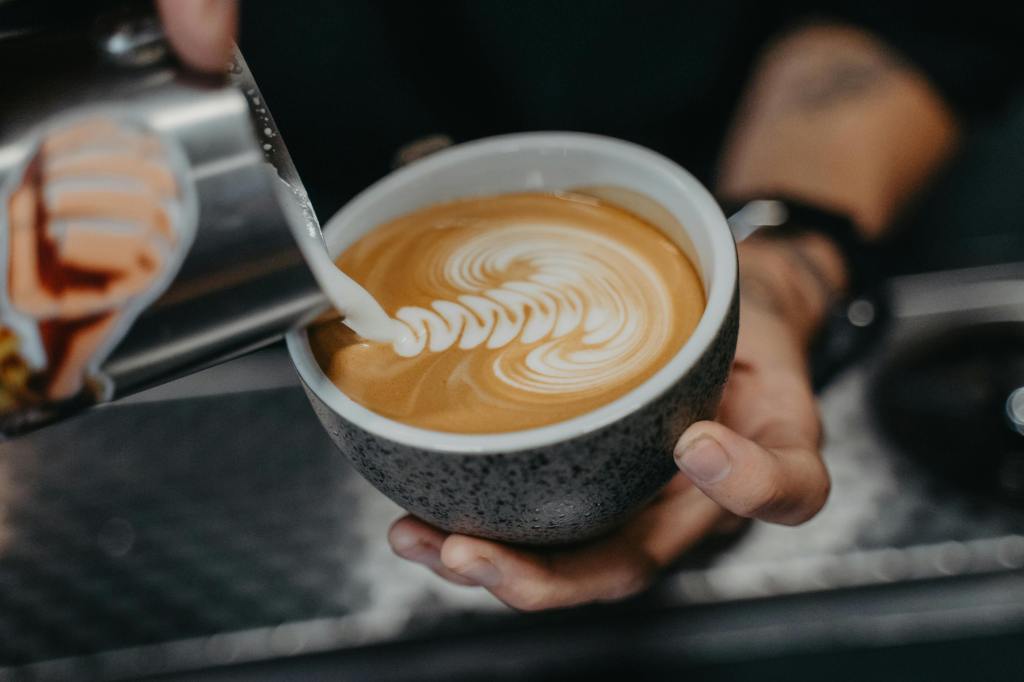 Ein Barista fertigt ein Milchschaum-Kunstwerk auf einem Kaffee an.