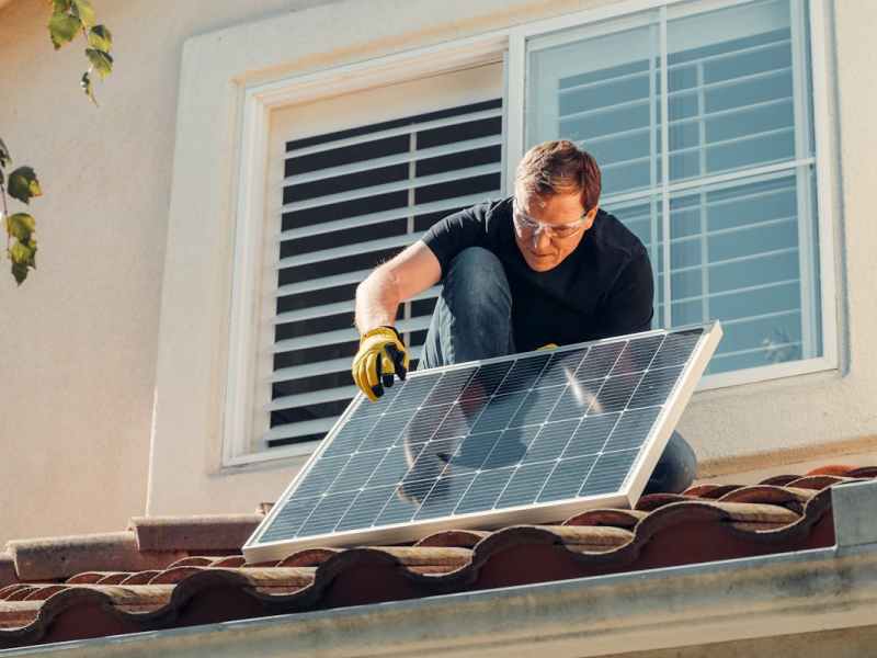 Mann installiert Solarpanel auf Dach