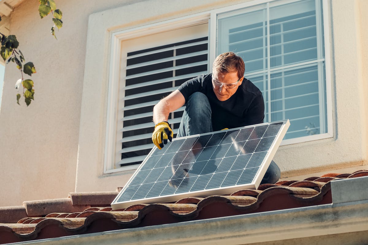 Mann installiert Solarpanel auf Dach