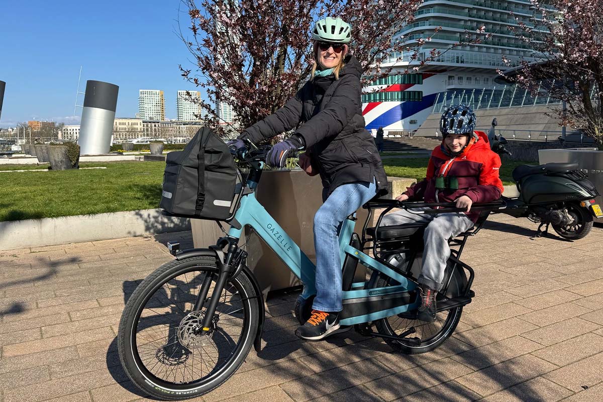 Frau auf einem Cargo-E-Bike, Kind sitzt hinten auf dem Rücksitz