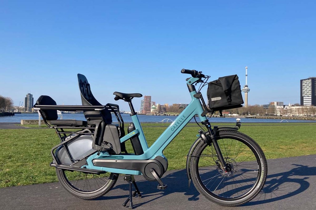 Totale Cargo-E-Bike mit Kindersitz, Städtskyline im Hintergrund